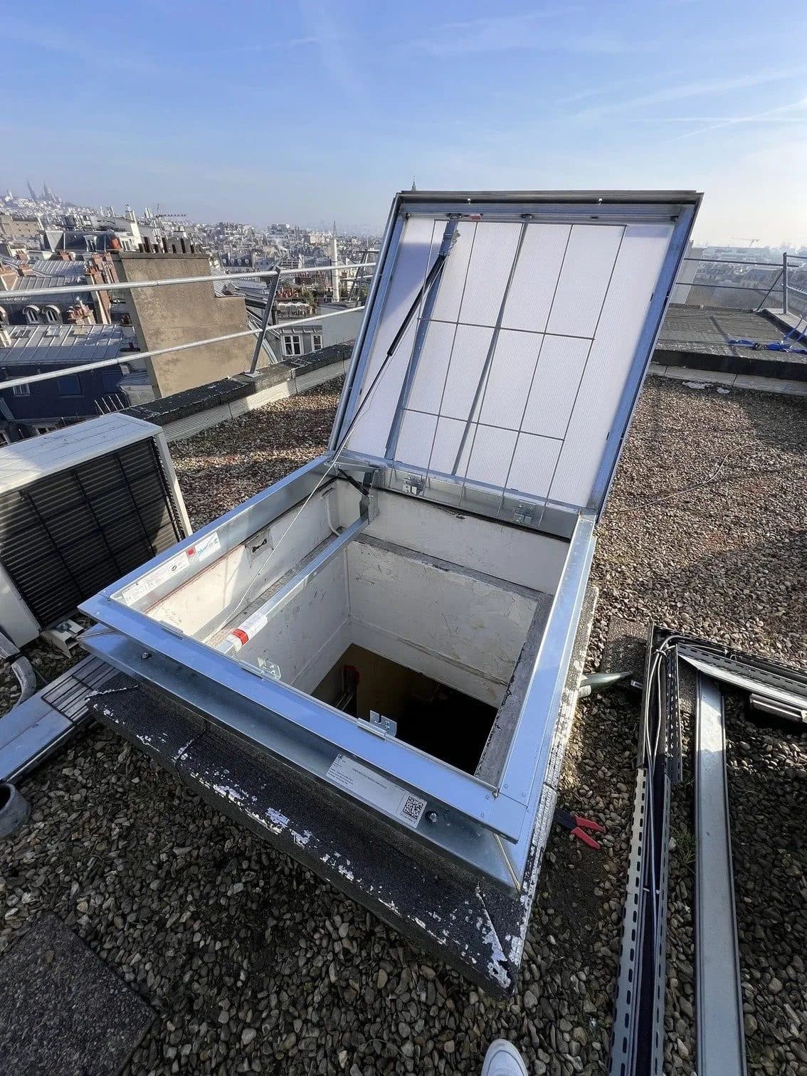 Exutoire de désenfumage ouvert en toiture-terrasse sur les toits de Paris, installé par AIRSECURE